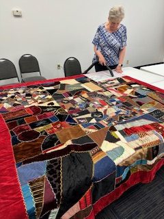 A volunteer inspects a Victorian crazy quilt from the collection